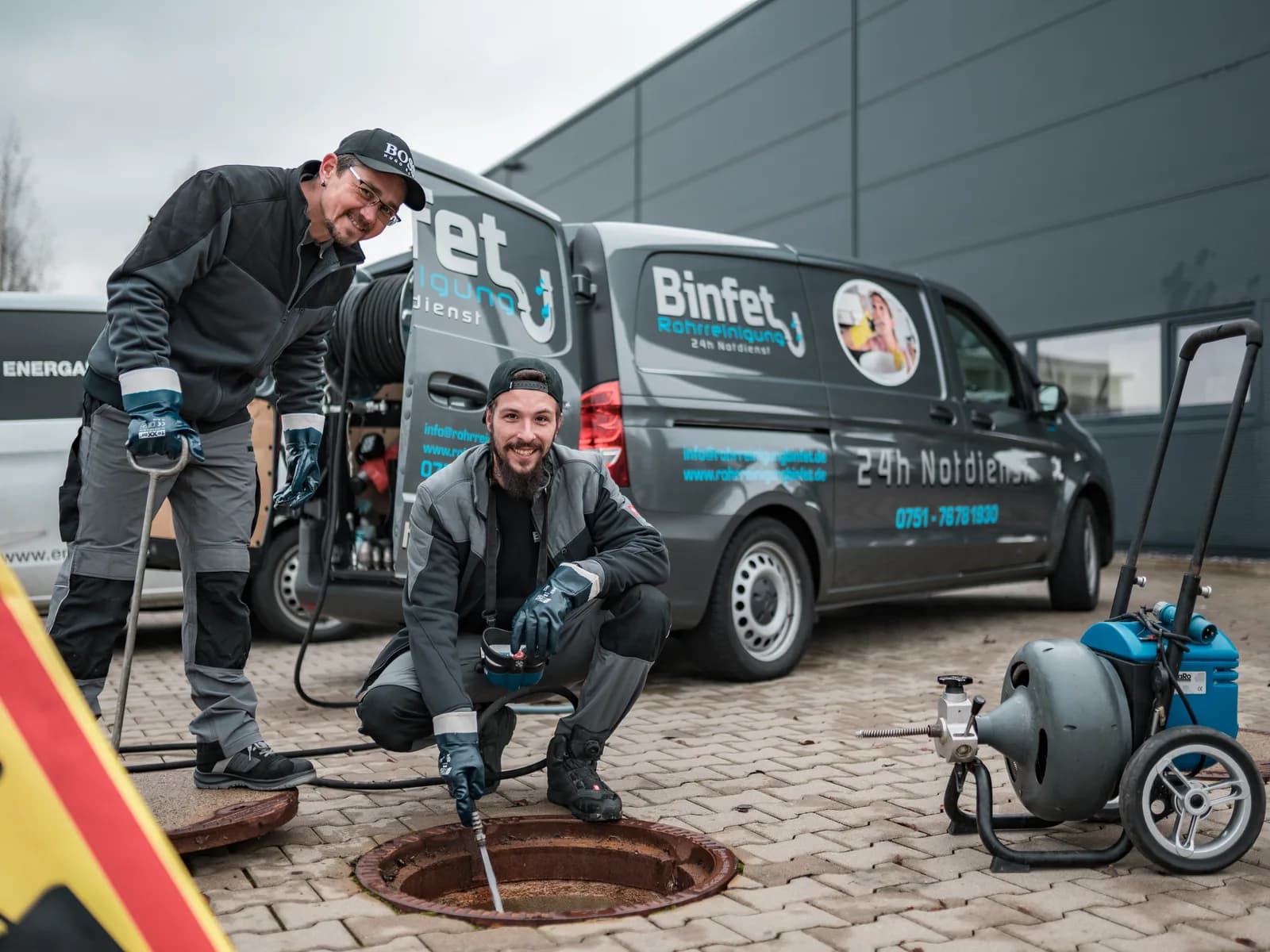 Zwei Techniker der Binfet Rohrreinigung arbeiten am geöffneten Kanalschacht